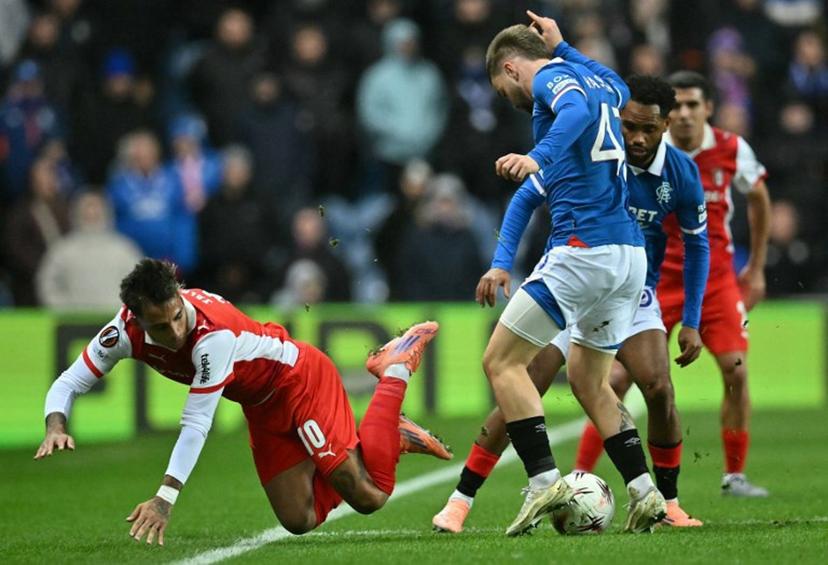 Sporting Braga's Uruguayan midfielder #10 Rodrigo Zalazar (L) falls to the pitch following a challenge from Rangers' Belgian midfielder #43 Nicolas Raskin during the UEFA Europa League league-stage football match between Rangers and CS Braga at the Ibrox Stadium in Glasgow on November 27, 2025.  ANDY BUCHANAN / AFP
