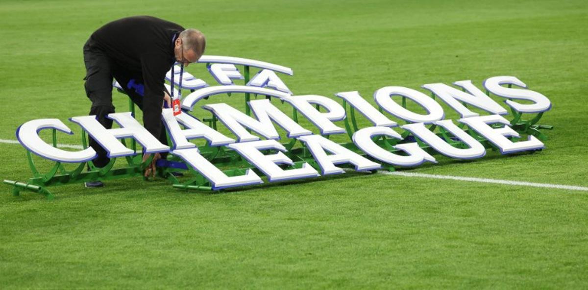 A worker sets up the 'UEFA - Champions League' logo on the field prior to the start of the UEFA Champions League quarter-final second leg football match between FC Bayern Munich and Real Madrid in Munich, southern Germany, on April 15, 2026.  Karl-Josef HILDENBRAND / AFP