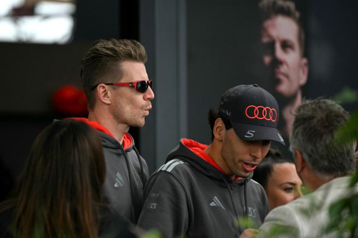 Audi's German driver Nico Hulkenberg (L) and Audi's Brazilian driver Gabriel Bortoleto (C) walk through the paddock ahead of the third practice session of the Formula One Australian Grand Prix at the Albert Park Circuit in Melbourne on March 7, 2026.    Paul Crock / AFP