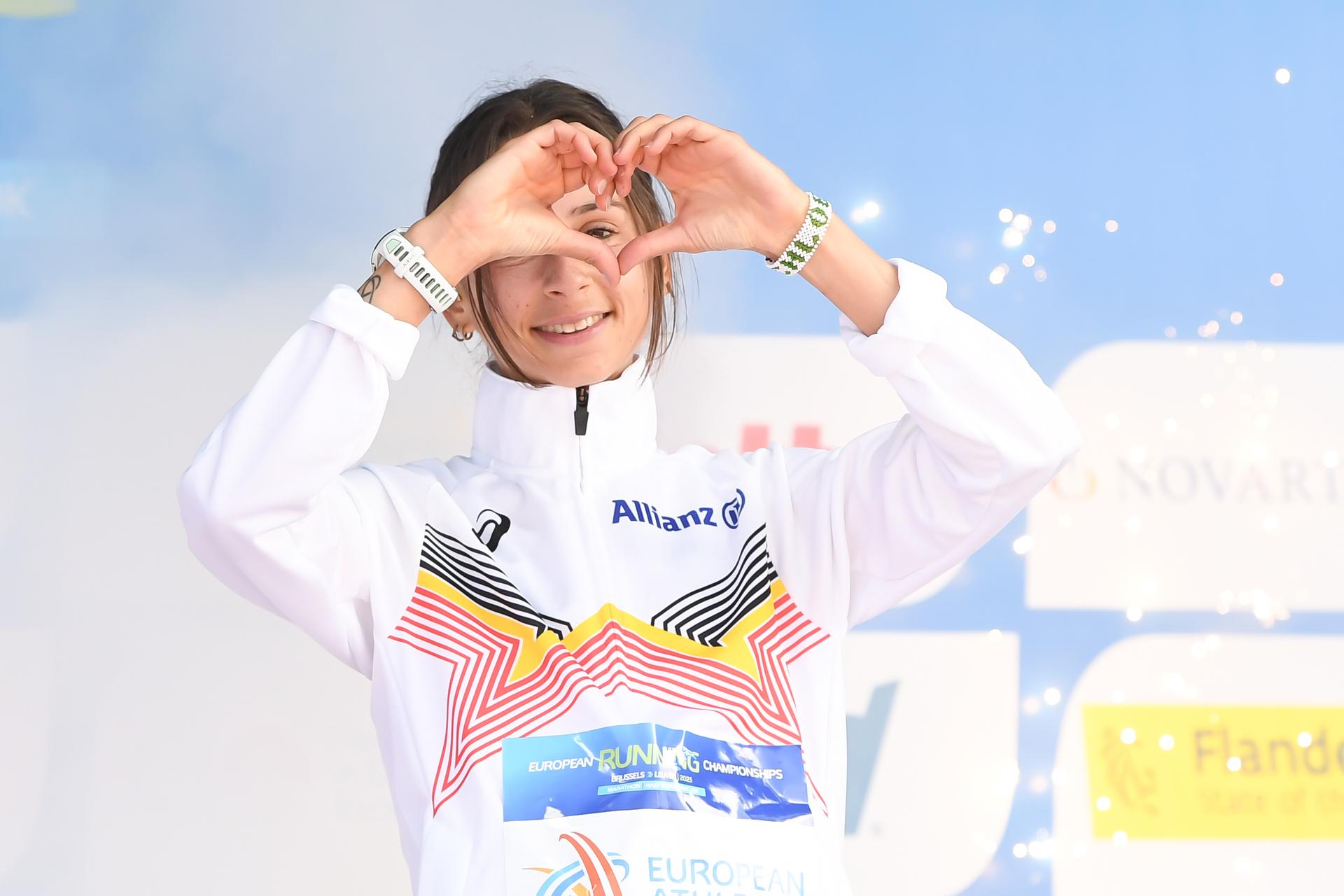 Belgian Chloe Herbiet celebrates on the podium after winning the half marathon race at European Running Championships, in Leuven, Saturday 12 April 2025. BELGA PHOTO JILL DELSAUX