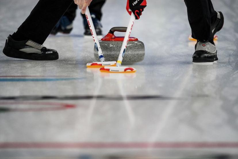 Competitors sweep in front of the curling stone during the men's bronze medal game of the Beijing 2022 Winter Olympic Games curling competition between Canada and USA at the National Aquatics Centre in Beijing on February 18, 2022.  Jeff PACHOUD / AFP