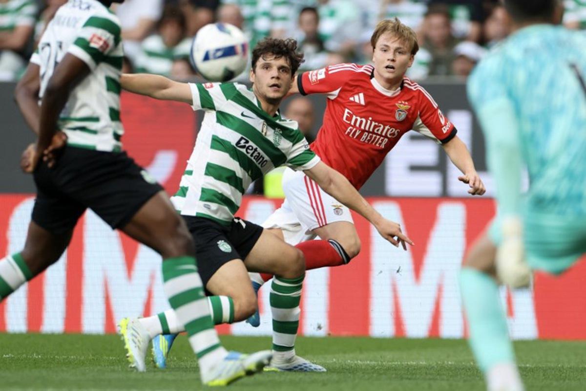 SL Benfica's Norwegian forward #21 Andreas Schjelderup  (R) wathces the ball challenged by Sporting Lisbon's Portuguese defender #72 Eduardo Quaresma during the Portuguese League football match between Sporting CP and SL Benfica at Jose Alvalade stadium in Lisbon, on April 19, 2026.  PATRICIA DE MELO MOREIRA / AFP