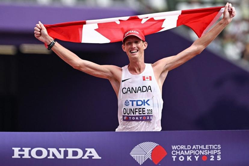 Canada's Evan Dunfee crosses the finish line with a Canadian flag to win the men's 35km race walk final during the World Athletics Championships in Tokyo on September 13, 2025.  Jewel SAMAD / AFP