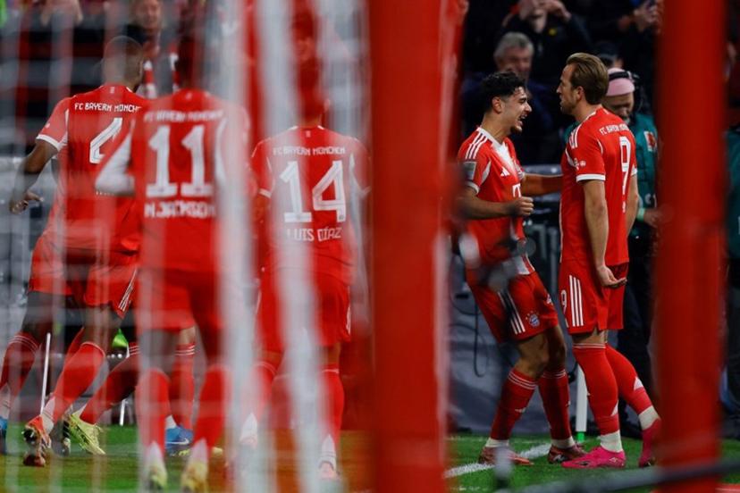Bayern Munich's English forward #09 Harry Kane celebrates scoring the opening goal with his teammates including Bayern Munich's Croatian defender #44 Josip Stanisic during the German first division Bundesliga football match FC Bayern Munich vs BVB Borussia Dortmund, in Munich, southern Germany on October 18, 2025.  Alexandra BEIER / AFP