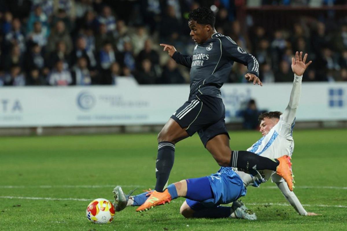 Real Madrid's Brazilian forward #16 Endrick fights for the ball with Talavera's Spanish defender #2 David Cuenca (down) during the Spanish Copa del Rey (King's Cup) round of 32 second leg football match between Talavera CF and Real Madrid CF at El Prado Municipal Stadium in Talavera de la Reina on December 17, 2025.  Thomas COEX / AFP