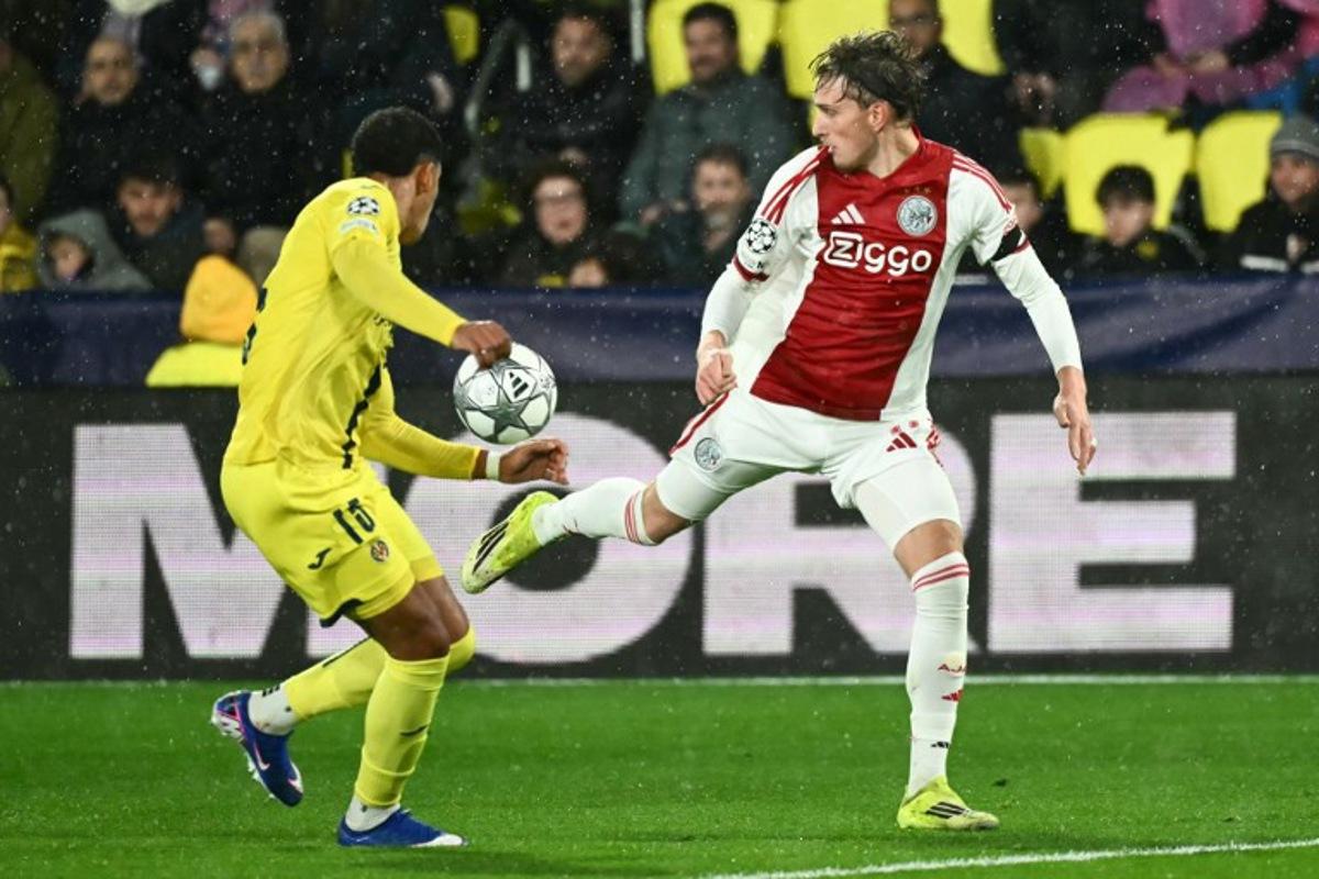 Ajax's Belgian forward #11 Mika Godts (R) controls the ball past Villarreal's Uruguayan defender #15 Santiago Mourino (L) during the UEFA Champions League league phase day 7 football match between Villarreal CF and Ajax at La Ceramica Stadium in Vila-real on January 20, 2026.  JOSE JORDAN / AFP