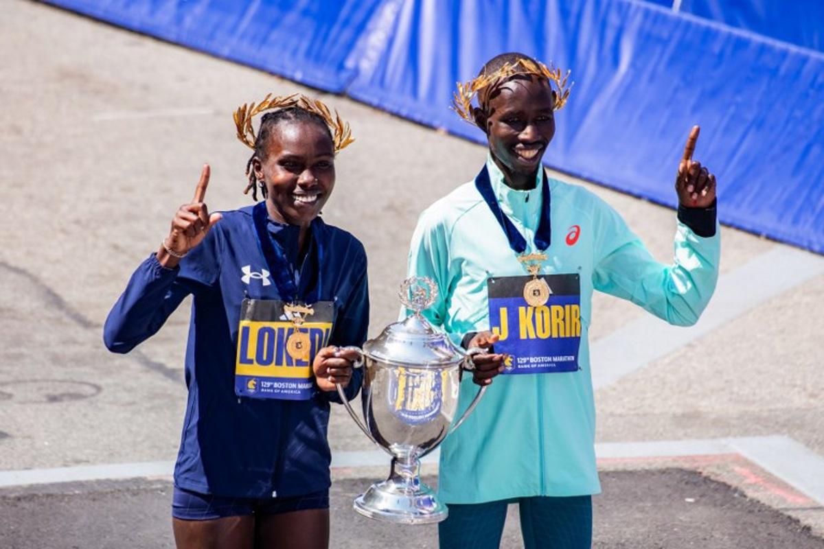 (L-R) Kenyan distance runners Sharon Lokedi and John Korir pose for pictures with the trophy after winning the women's and men's races, respectively, during the 129th Boston Marathon on April 21, 2025, in Boston, Massachusetts.  The marathon includes around 30,000 athletes from 129 countries running the 26.2 miles from Hopkinton to Boston, Massachusetts.  The event is the world's oldest annually run marathon.  Joseph Prezioso / AFP