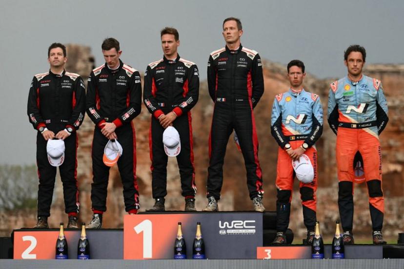 British driver Elfyn Evans (2nd L) and co-driver Scott Martin, French driver Sebastien Ogier (3rd R) and co-driver Vincent Landais, and Belgium driver Thierry Neuville (R) and co-driver Martijn Wydaeghe listen to the anthems at the podium of the WRC Rally Paraguay, 10th stage of the FIA World Rally Championship (WRC), at the Ruins of Trinidad, Itapua department, Paraguay on August 31, 2025.  Luis ROBAYO / AFP
