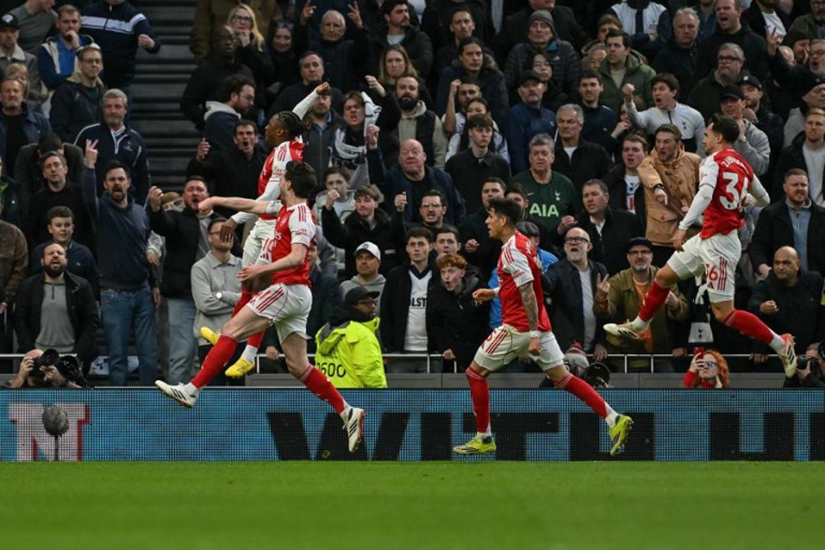 Arsenal's English midfielder #10 Eberechi Eze (far L) jumps with teammates as they celebrate after he scores the team's first goal during the English Premier League football match between Tottenham Hotspur and Arsenal at the Tottenham Hotspur Stadium in London, on February 22, 2026.  Glyn KIRK / AFP