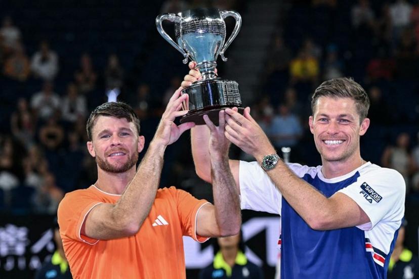 Great Britain's Neal Skupski (R) and his partner USA's Christian Harrison celebrate with the trophy after winning their men's doubles final match against Australia's Jason Kubler and Marc Polmans on day fourteen of the Australian Open tennis tournament in Melbourne on January 31, 2026.  WILLIAM WEST / AFP