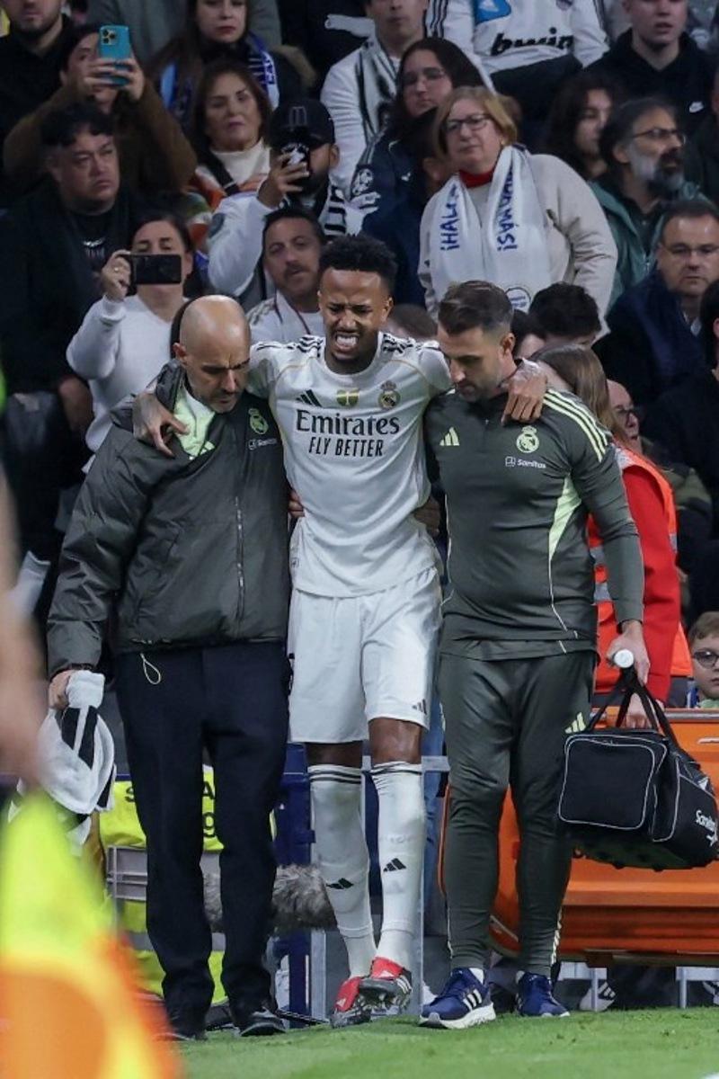 Real Madrid's Brazilian defender #03 Eder Militao walks off with assistance after sustaining an injury during the Spanish league football match between Real Madrid CF and RC Celta de Vigo at the Santiago Bernabeu Stadium in Madrid on December 7, 2025.  Thomas COEX / AFP