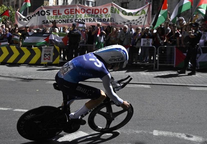 Pro-Palestinians protesters wave Palestinian flags as Team Israel Premier Tech's Israeli rider Nadav Raisberg competes during the 18th stage of the Vuelta a Espana, a 26 km race against the clock between Valladolid and Valladolid, on September 11, 2025.    Miguel RIOPA / AFP