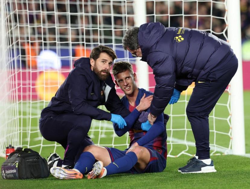 Medical staff's members tend to Barcelona's Spanish midfielder #20 Daniel Olmo injured after scoring during the Spanish league football match between FC Barcelona and Club Atletico de Madrid at Camp Nou Stadium in Barcelona on December 2, 2025.  Lluis GENE / AFP
