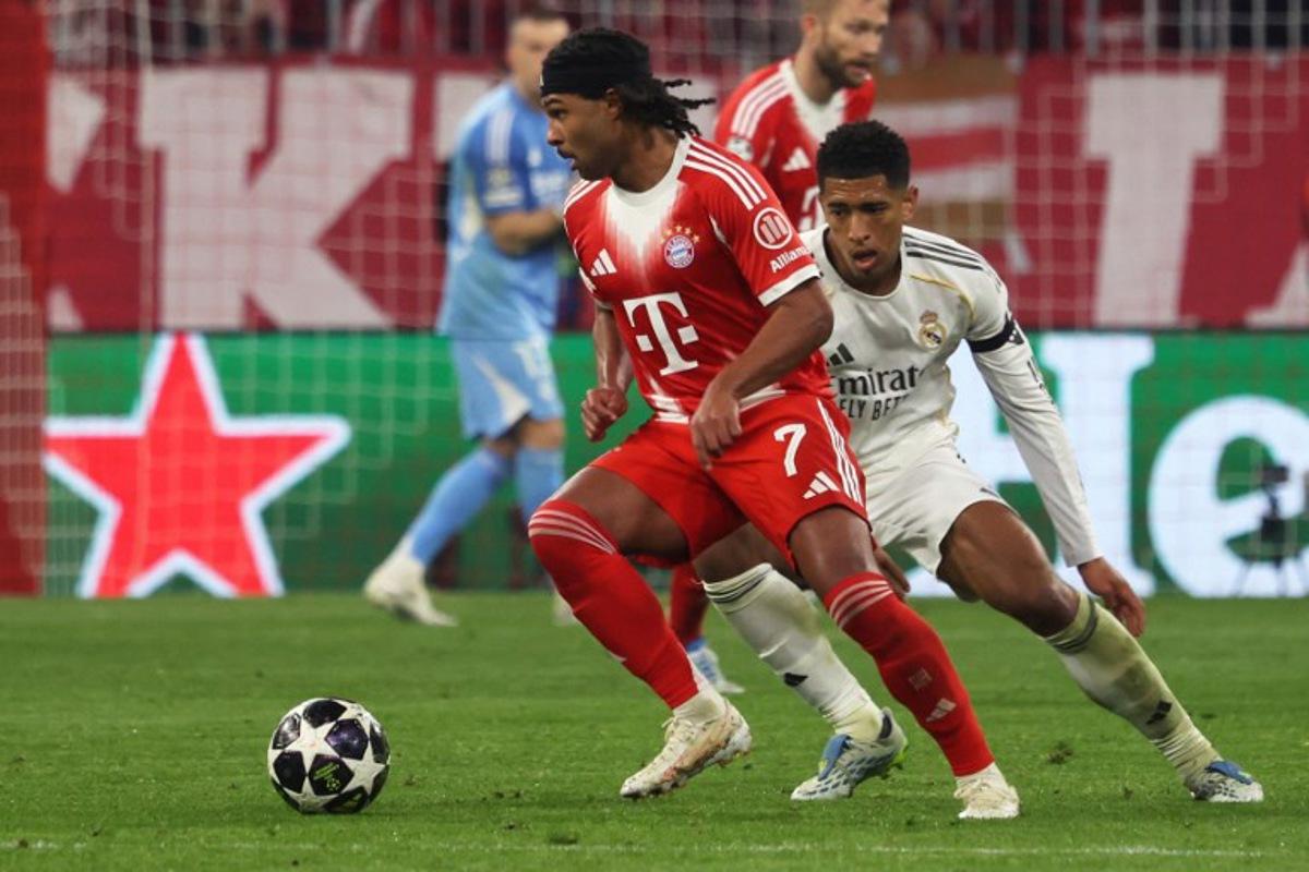 Real Madrid's English midfielder #05 Jude Bellingham (R) and Bayern Munich's German forward #07 Serge Gnabry vie for the ball during the UEFA Champions League quarter-final second leg football match between FC Bayern Munich and Real Madrid in Munich, southern Germany, on April 15, 2026.  Karl-Josef HILDENBRAND / AFP