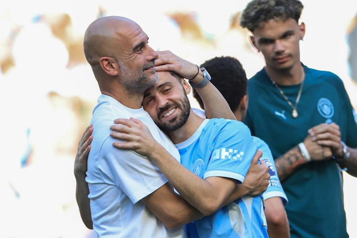 Manchester City's Spanish manager Pep Guardiola (L) embraces Manchester City's Portuguese midfielder #20 Bernardo Silva (C) during ceremonies following the English Premier League football match between Manchester City and Aston Villa at the Etihad Stadium in Manchester, north west England, on May 24, 2026.  Darren Staples / AFP