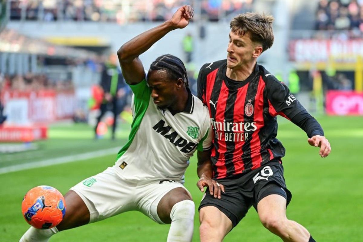 Sassuolo's Canadian midfielder #90 Ismaël Koné fights for the ball with AC Milan's Belgian midfielder #56 Alexis Saelemaekers during the Italian Serie A football match between AC Milan and Sassuolo at the San Siro Stadium in Milan, Italy on December 14, 2025.  Piero CRUCIATTI / AFP