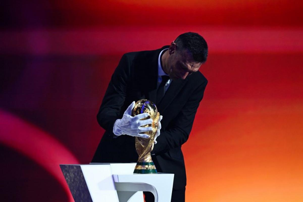 Argentina's head coach Lionel Scaloni places the FIFA World Cup trophy on stage during the draw for the 2026 FIFA Football World Cup taking place in the US, Canada and Mexico, at the Kennedy Center, in Washington, DC, on December 5, 2025.  SAUL LOEB / AFP