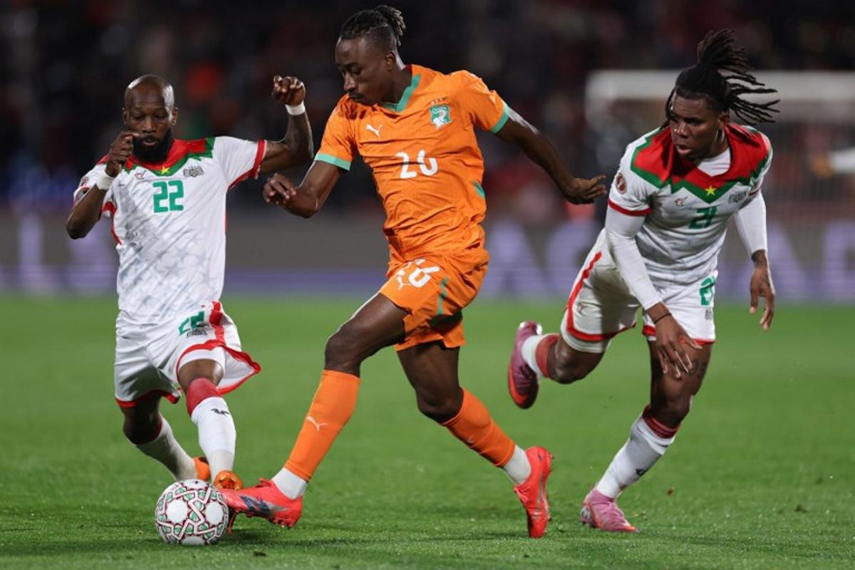 Burkina Faso's midfielder #22 Ibrahim Blati Toure (L) closes in on Ivory Coast's forward #26 Yan Diomande with Burkina Faso's forward #21 Cyriaque Irie Bi during the Africa Cup of Nations (CAN) round of 16 football match between Ivory Coast and Burkina Faso at the Grand Stadium in Marrakesh on January 6, 2026.   FRANCK FIFE / AFP