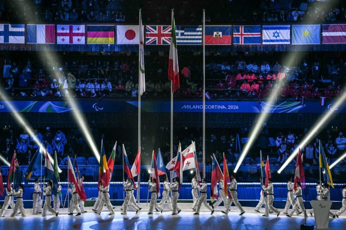 Volunteers parade with flags of countries during the Milano Cortina 2026 Winter Paralympic Games closing ceremony at the Olympic Ice Stadium in Cortina d'Ampezzo, on March 15, 2026.  Jeff PACHOUD / AFP