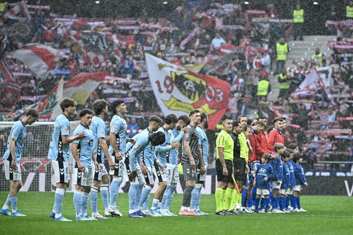 Teams line up under the rain before the start of the Spanish league football match between Club Atletico de Madrid and RC Celta de Vigo at the Metropolitano Stadium in Madrid on May 9, 2026.  Javier SORIANO / AFP
