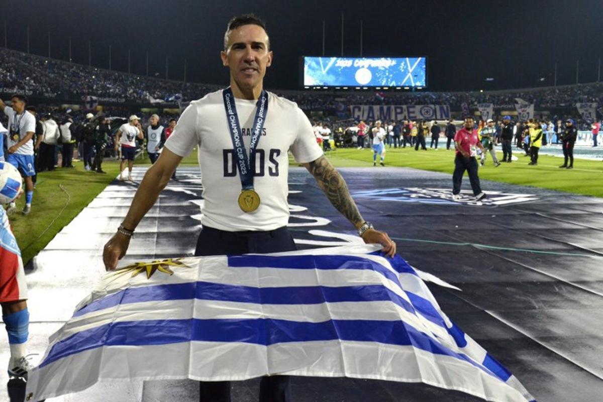 Cruz Azul's Uruguayan interim coach Vicente Sanchez poses with an Uruguayan flag after winning the CONCACAF Champions Cup final football match between Mexico's Cruz Azul and Canada's Vancouver Whitecaps at the Olimpico Universitario Stadium in Mexico City on June 1, 2025.  Victor CRUZ / AFP