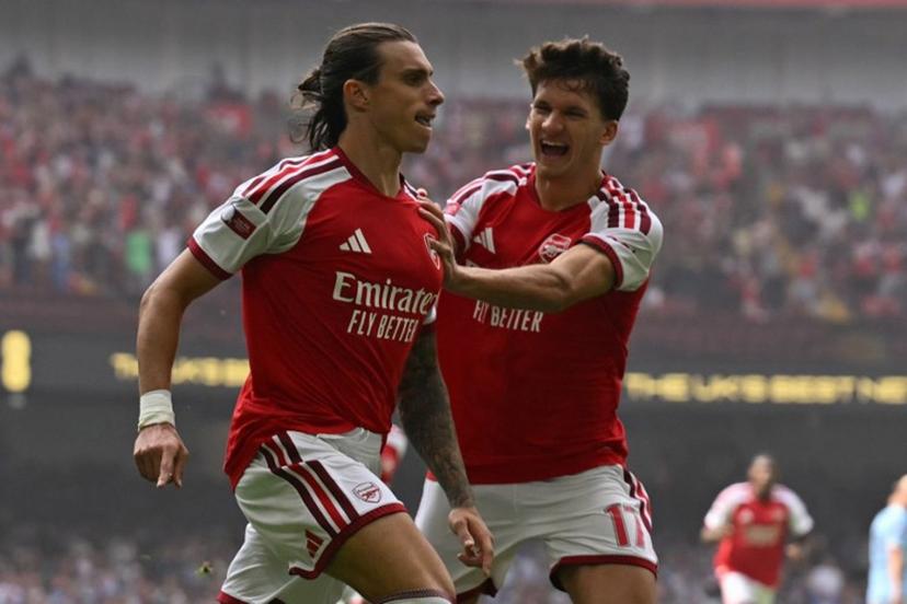 Arsenal's Italian defender #33 Riccardo Calafiori (L) celebrates with Arsenal's Greek striker #17 Christos Tzolis (R) after scoring the opening goal of the English FA Community Shield football match between Arsenal and Manchester City at The Principality Stadium, in Cardiff, south Wales on August 16, 2026.  Glyn KIRK / AFP