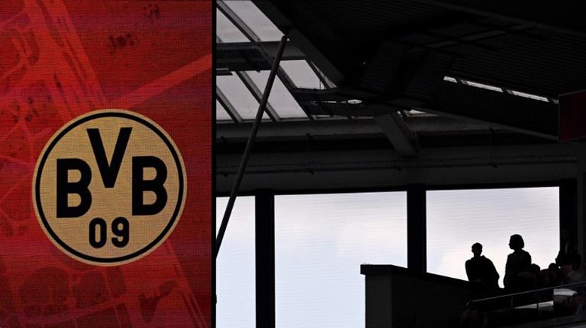 Football fans are seen on the stands next to a display with the BVB Borussia Dortmund logo during the German first division Bundesliga football match between 1 FSV Mainz 05 and Borussia Dortmund in Mainz, western Germany on September 27, 2025.  Kirill KUDRYAVTSEV / AFP
