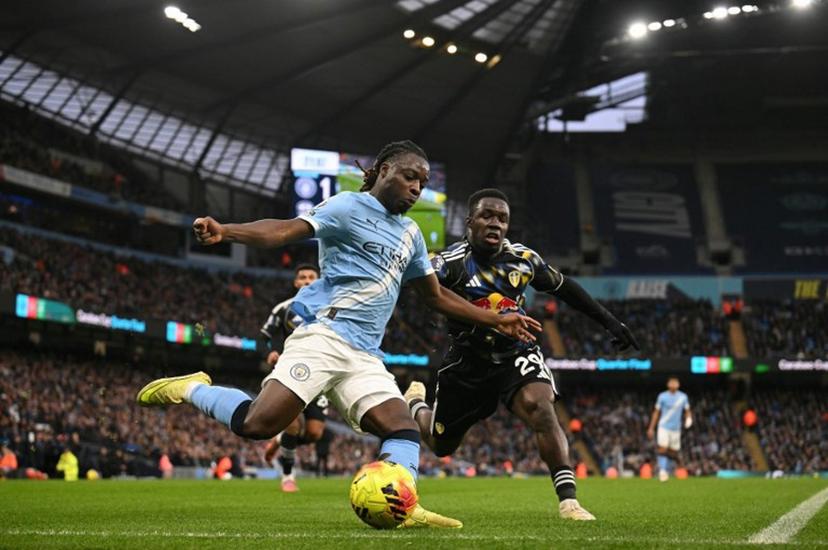 Manchester City's Belgian midfielder #11 Jeremy Doku (L) crosses the ball during the English Premier League football match between Manchester City and Leeds United at the Etihad Stadium in Manchester, north west England, on November 29, 2025.  Oli SCARFF / AFP
