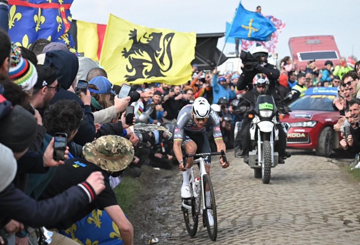 A spectator spills liquid as Alpecin-Deceuninck's Dutch rider Mathieu van der Poel cycles during the 122nd edition of the Paris-Roubaix one-day classic cycling race, 259,2 km between Compiegne and Roubaix, northern France on April 13, 2025.  Bernard PAPON / POOL / AFP