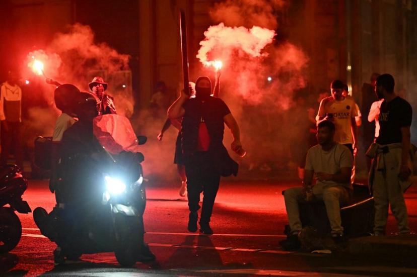 Paris Saint-Germain (PSG) supporters gather holding flares on a street in Paris early June 1, 2025, during celebrations following their 5-0 victory in the UEFA Champions League final football match between Paris Saint-Germain (PSG) and Inter Milan held in Munich.  LOU BENOIST / AFP