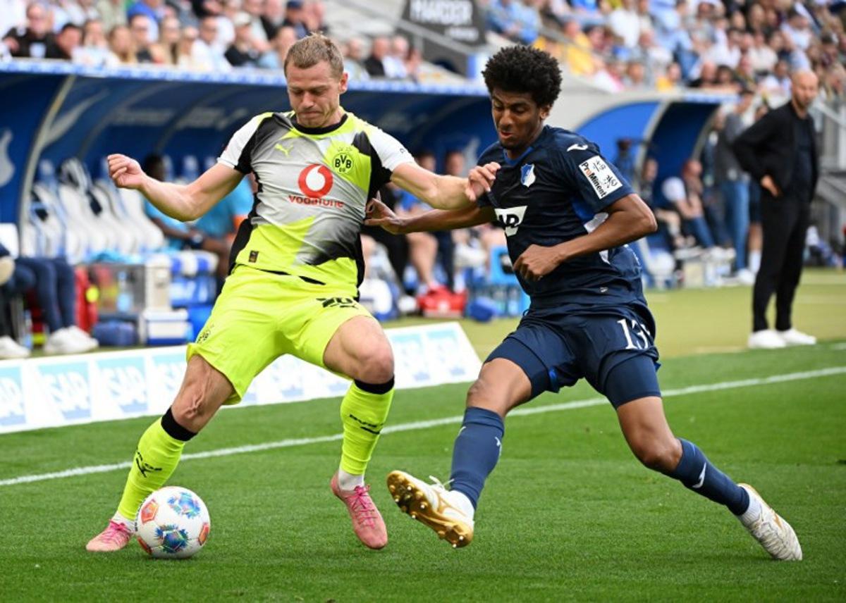 Dortmund's Norwegian defender #26 Julian Ryerson (L) and Hoffenheim's Brazilian defender #13 Bernardo vie for the ball during the German first division Bundesliga football match between TSG 1899 Hoffenheim and BVB Borussia Dortmund in Sinsheim, southwestern Germany on April 18, 2026.  Uli Deck / AFP