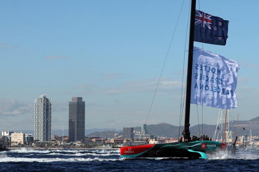 Members of the crew of defender Emirates Team New Zealand hoist a flagf reading in Catalan "Thanks a lot Barcelona" as they celebrate winning the Louis Vuitton 37th America's Cup Match, in Barcelona on October 19, 2024.  LLUIS GENE / AFP