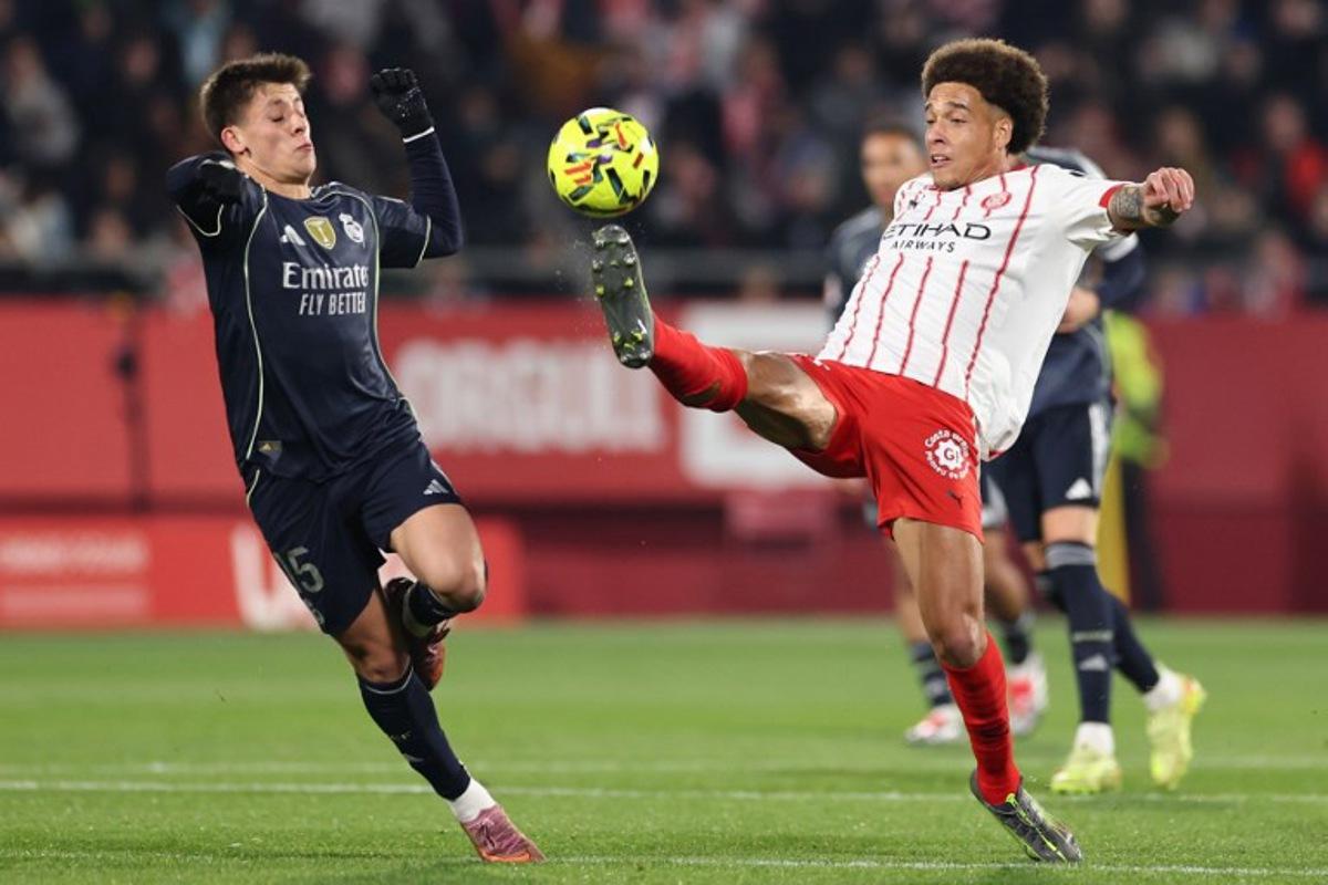 Real Madrid's Turkish midfielder #15 Arda Guler (L) fights for the ball with Girona's Belgian defender #20 Axel Witsel during the Spanish league football match between Girona FC and Real Madrid CF at Montilivi Stadium in Girona on November 30, 2025.  Josep LAGO / AFP