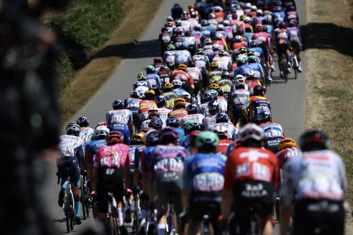 The pack of riders (peloton) cycles during the 8th stage of the 112th edition of the Tour de France cycling race, 171.4 km between Saint-Meen-le-Grand and Laval Espace Mayenne, western France, on July 12, 2025.  Anne-Christine POUJOULAT / AFP
