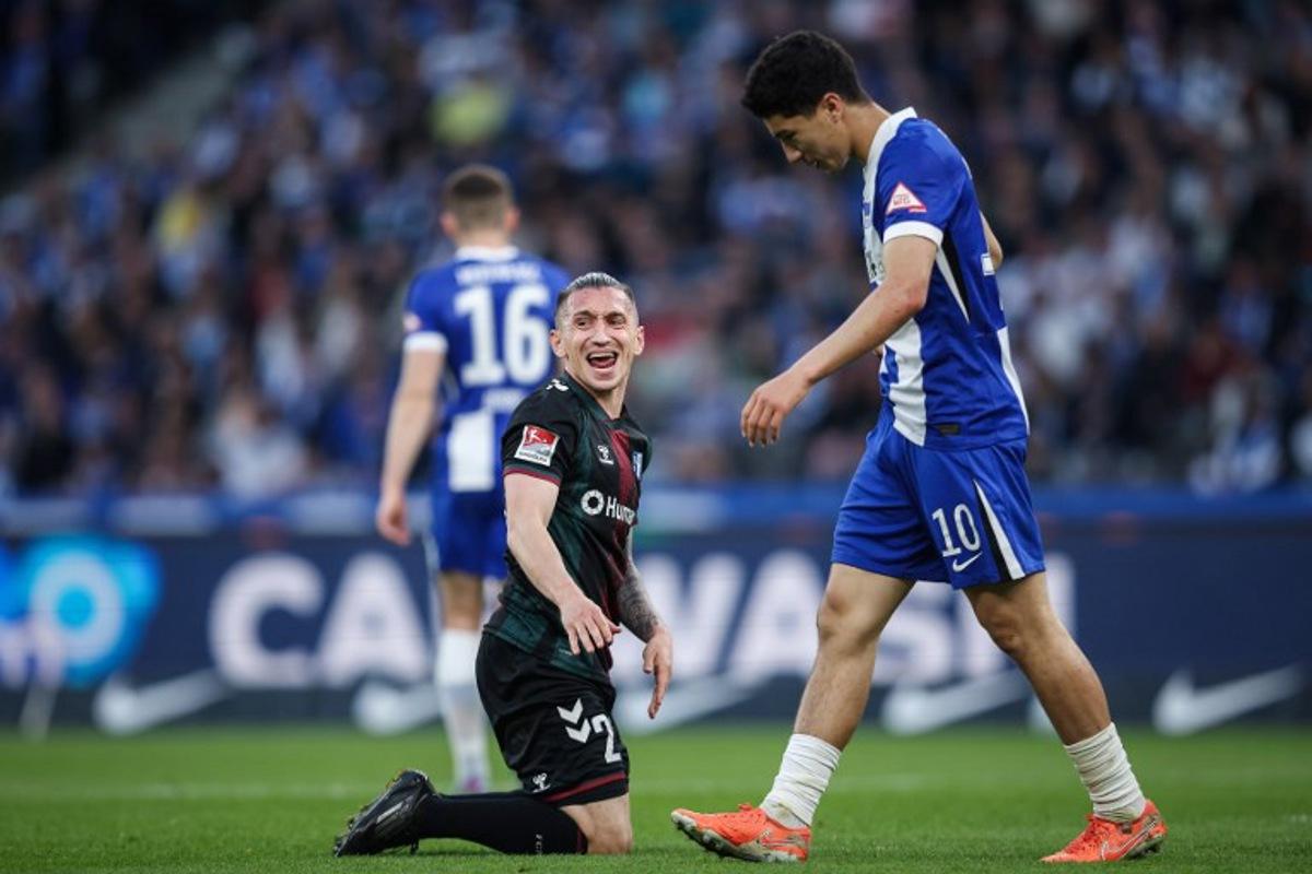 Magdeburg's Turkish forward #23 Baris Atik (L) reacts next to Berlin's Algerian forward #10 Ibrahim Maza (R) during the Bundesliga second division football match between Hertha BSC vs 1 FC Magdeburg at the Olympic Stadium (Olympiastadion) in Berlin, Germany on April 25, 2025. Driven by huge crowds, unpredictable results and some of Germany's biggest clubs, the Bundesliga 2 broke through the billion euro barrier last season to become Europe's wealthiest second flight. Ronny Hartmann / AFP