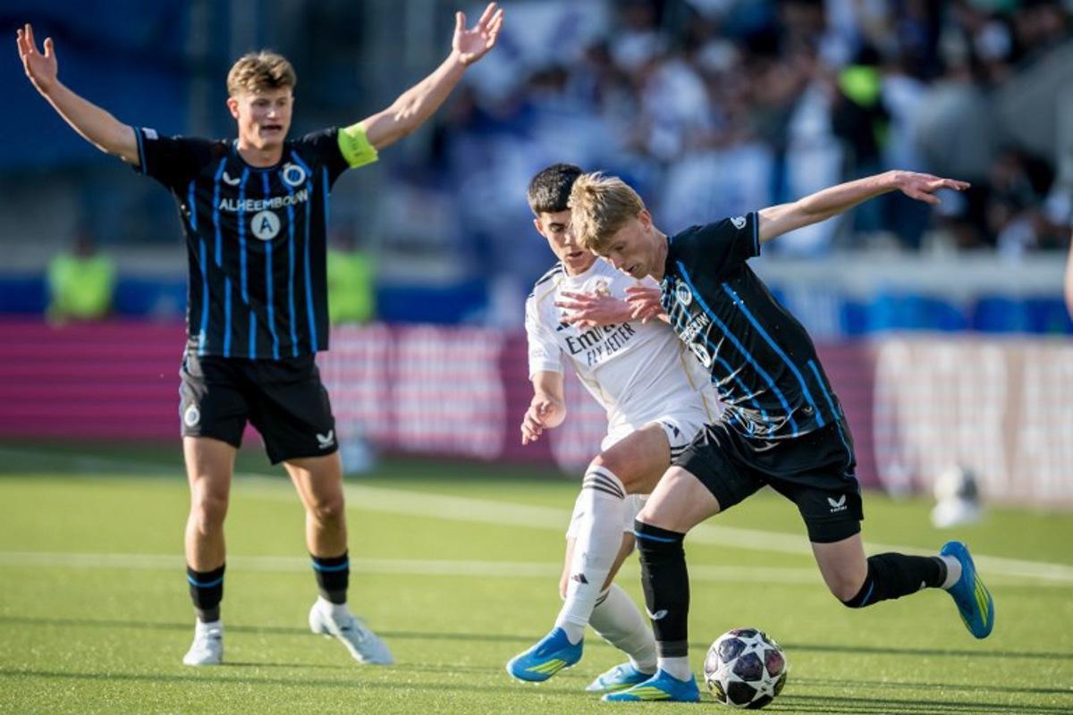 Real Madrid's Spanish defender #37 Alvaro Lezcano (C) fights for the ball with Club Brugge's Danish midfielder #78 Tobias Lund Jensen during the UEFA Youth League final football match between Club Brugge and Real Madrid at Stade de la Tuiliere in Lausanne, on April 20, 2026.  Fabrice COFFRINI / AFP