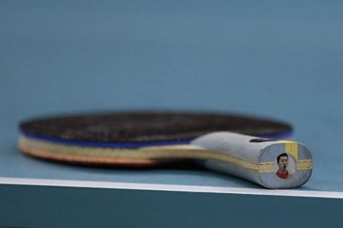 China's Ma Long's racket is seen on the table with his own picture on the end in the men's team gold medal table tennis match against Japan's Maharu Yoshimura at the Riocentro venue during the Rio 2016 Olympic Games in Rio de Janeiro on August 17, 2016. 
Juan Mabromata / AFP
