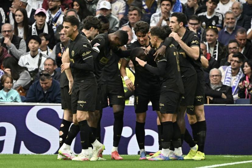 Valencia players celebrate scoring their first goal during the Spanish league football match between Real Madrid CF and Valencia CF at the Santiago Bernabeu stadium in Madrid on April 5, 2025.  JAVIER SORIANO / AFP