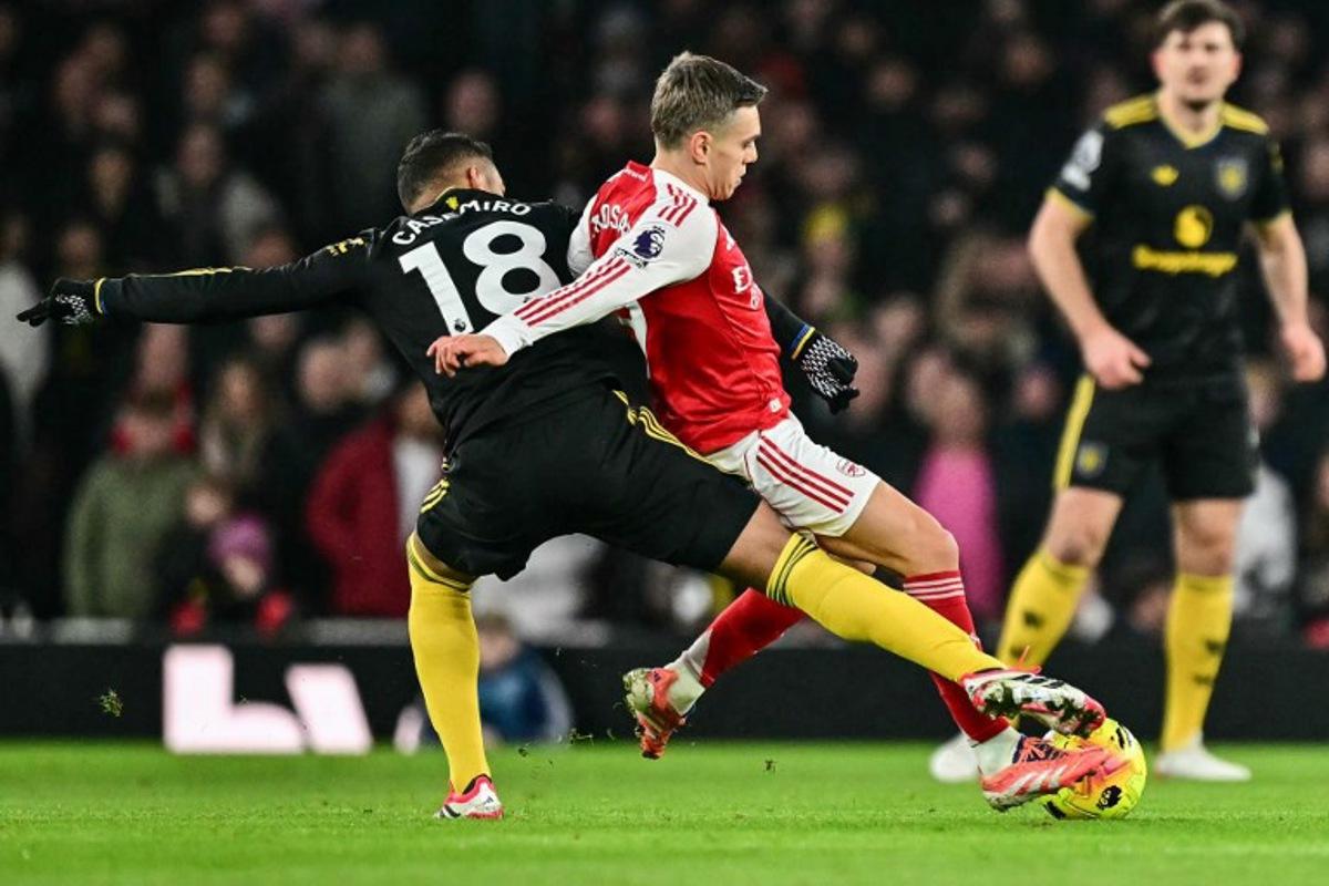 Manchester United's Brazilian midfielder #18 Casemiro (L) brings down Arsenal's Belgian midfielder #19 Leandro Trossard (C) for a free kick during the English Premier League football match between Arsenal and Manchester United at the Emirates Stadium in London on January 25, 2026.   Ben STANSALL / AFP