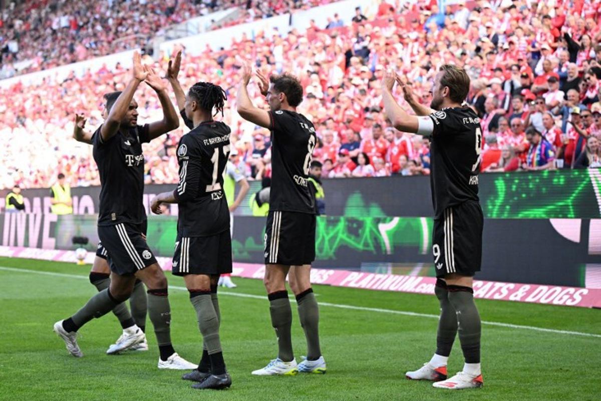 Bayern Munich's English forward #09 Harry Kane celebrates with team mates after scoring his team's fourth goal 3:4 during the German first division Bundesliga football match between 1 FSV Mainz 05 and FC Bayern Munich in Mainz, western Germany on April 25, 2026.  Kirill KUDRYAVTSEV / AFP
