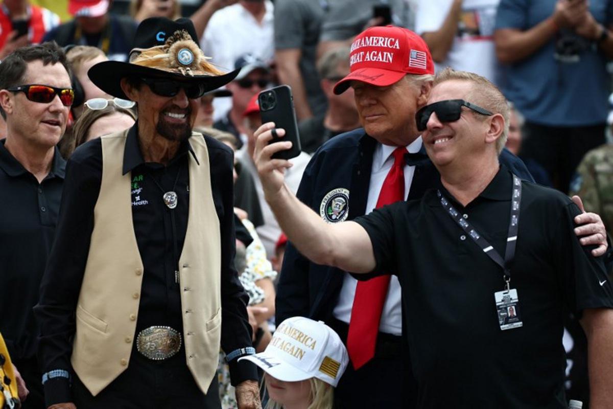 US PPresident Donald Trump takes a selfie with former NASCAR Cup series driver, Greg Biffle (R) and NASCAR Hall of Famer, Richard Petty prior to the NASCAR Cup Series Daytona 500 at Daytona International Speedway on February 16, 2025 in Daytona Beach, Florida.  Chris Graythen / POOL / AFP