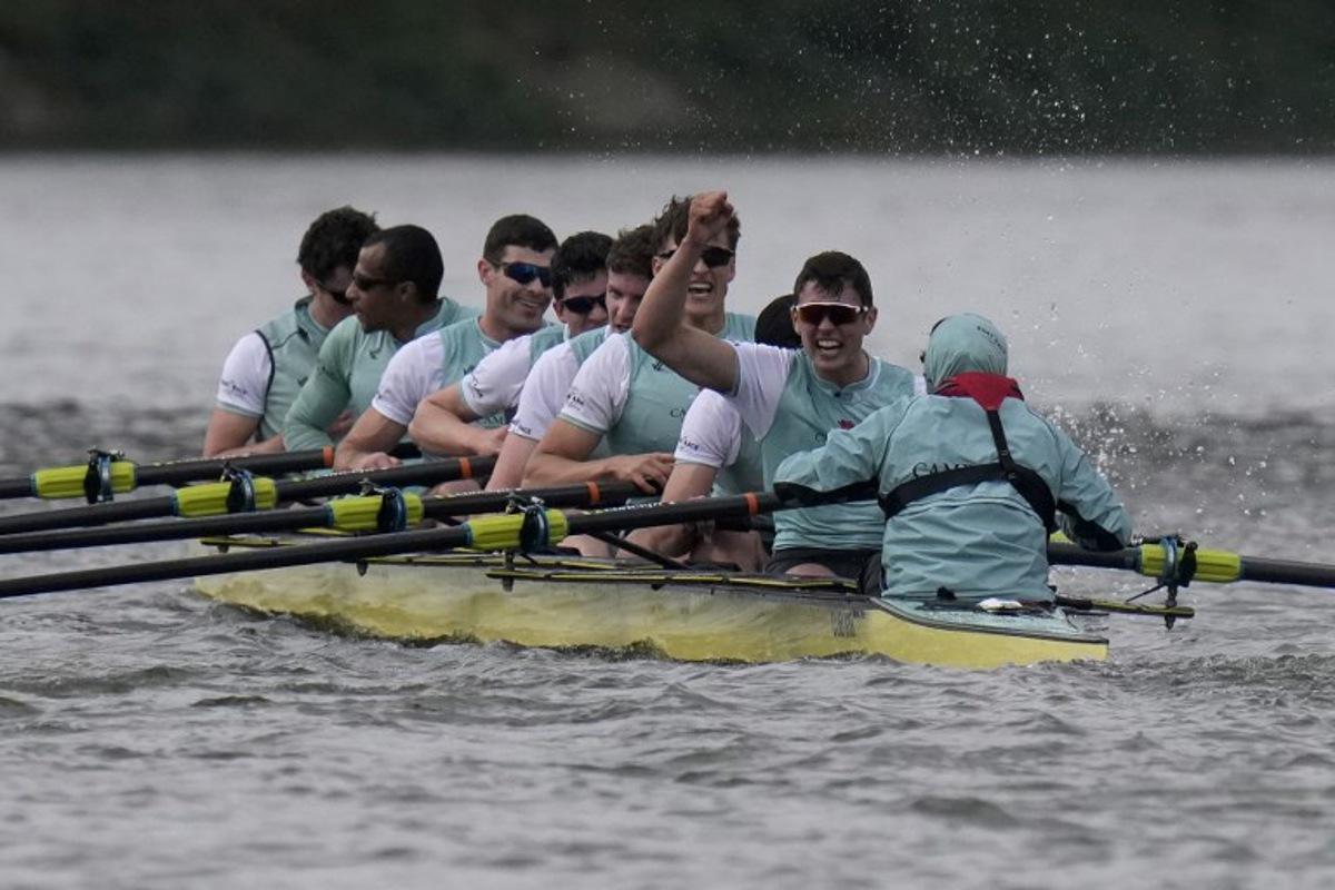 (R-L) Cambridge's Cox, Sammy Houdagui and rowers Freddy Breuer, Will Klipstine, Lexi McClean, Gabriel Obholzer, Patrick Wild, Kyle Fram, French president, Noam Mouelle, and Simon Hatcher celebrate winning the 171th men's boat race between Oxford University and Cambridge University on the River Thames in London on April 4, 2026.   CARLOS JASSO / AFP