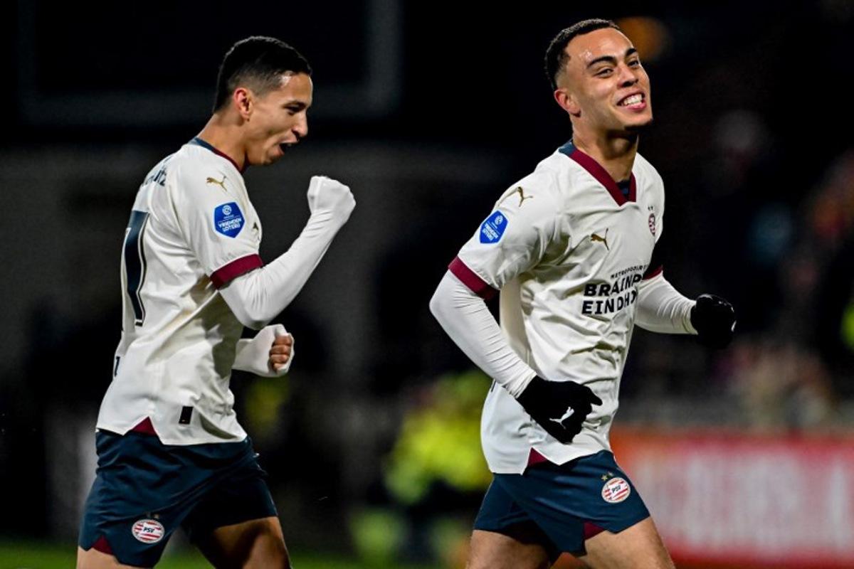 PSV's US midfielder #08 Sergino Dest (R) celebrates scoring his team's first goal with teammate PSV's Brazilian defender #17 Mauro Junior (L) during the Dutch Eredivisie football match between Go Ahead Eagles and PSV Eindhoven at De Adelaarshorst stadium in Deventer on March 8, 2024.  Gerrit van Keulen / ANP / AFP