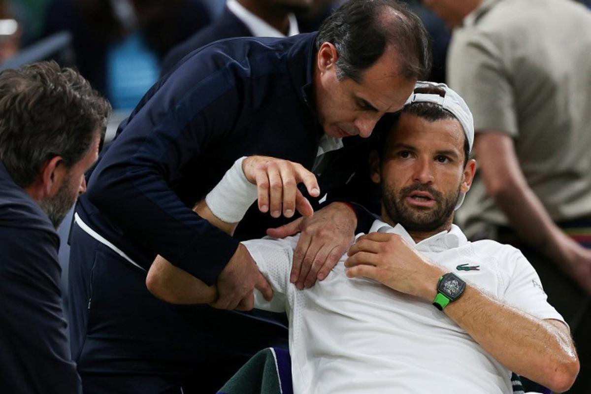 Bulgaria's Grigor Dimitrov reacts as he receives medical treatment after getting injured as he plays against Italy's Jannik Sinner during their men's singles fourth round tennis match on the eighth day of the 2025 Wimbledon Championships at The All England Lawn Tennis and Croquet Club in Wimbledon, southwest London, on July 7, 2025.  Adrian Dennis / AFP