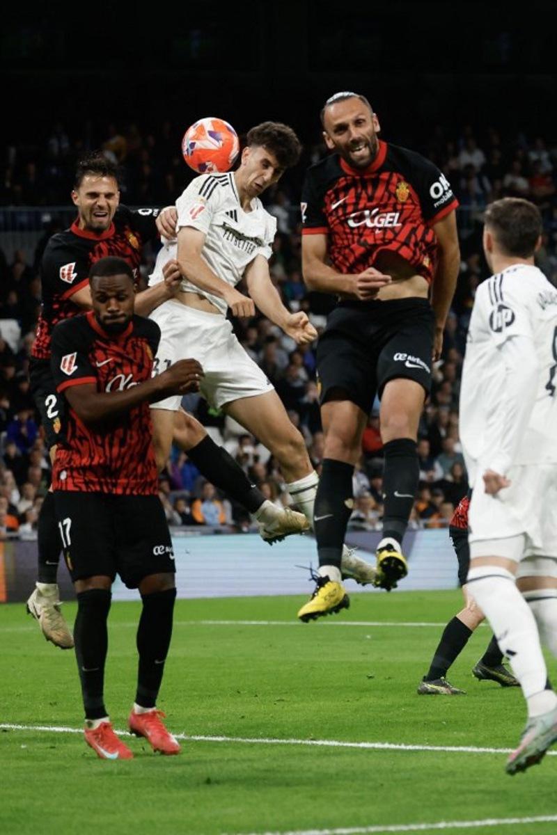 Real Madrid's Spanish defender #31 Jacobo Ramon (C) and Real Mallorca's Kosovo forward #07 Vedat Muriqi go for a header during the Spanish league football match between Real Madrid CF and RCD Mallorca at the Santiago Bernabeu Stadium in Madrid, on May 14, 2025.  Pierre-Philippe MARCOU / AFP