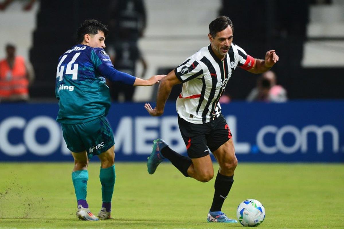 Talleres' defender #44 Santiago Fernandez and Libertad's forward #24 Roque Santa Cruz fight for the ball during the Copa Libertadores group stage football match between Paraguay's Libertad and Argentina's Talleres de Cordoba, at the La Huerta stadium in Asuncion, on April 8, 2025.  DANIEL DUARTE / AFP