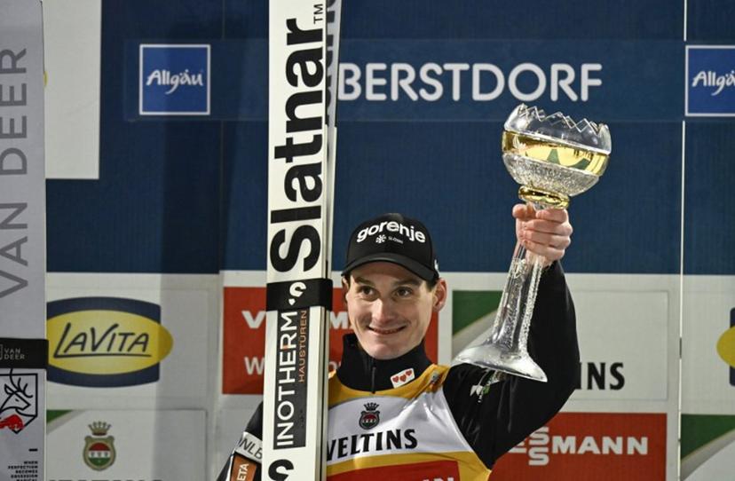 Winner, Slovenia's Domen Prevc, celebrates on the podium with his trophy after the second jump of the Men's Individual Large Hill HS137 event of the FIS Ski Jumping World Cup, the first leg of the Four Hills Tournament, in Oberstdorf, southern Germany on December 29, 2025.  PHILIPP GUELLAND / AFP