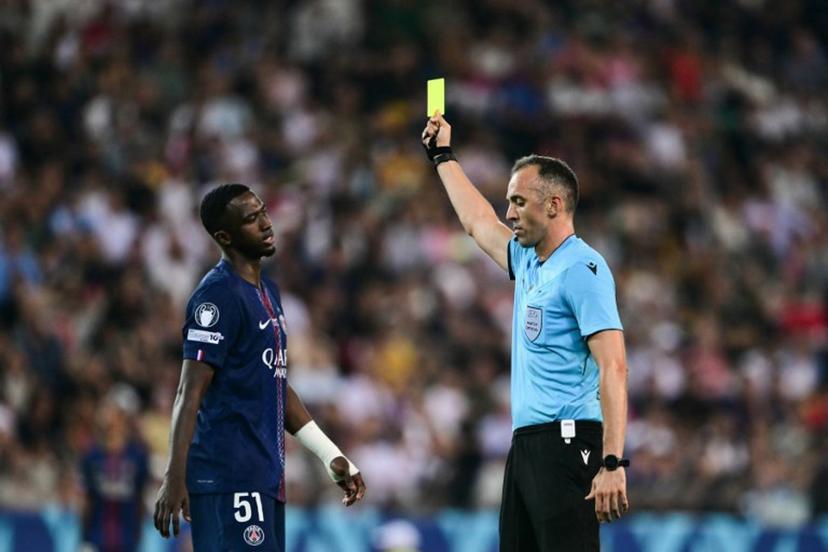 Portuguese referee Joao Pinheiro (R) shows Paris Saint-Germain's Ecuadoran defender #51 Willian Pacho (L) a yellow card as he books him for a foul during the 2025 UEFA Super Cup final football match between Paris Saint-Germain (FRA) and Tottenham Hotspur FC (ENG) at the Friuli stadium, in Udine, on August 13, 2025.  Marco BERTORELLO / AFP