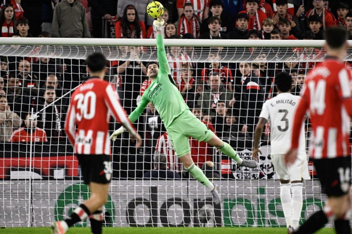 Real Madrid's Belgian goalkeeper #01 Thibaut Courtois leaps for the ball to make a save during the Spanish league football match between Athletic Club Bilbao and Real Madrid CF at the San Mames stadium in Bilbao on December 3, 2025.  ANDER GILLENEA / AFP