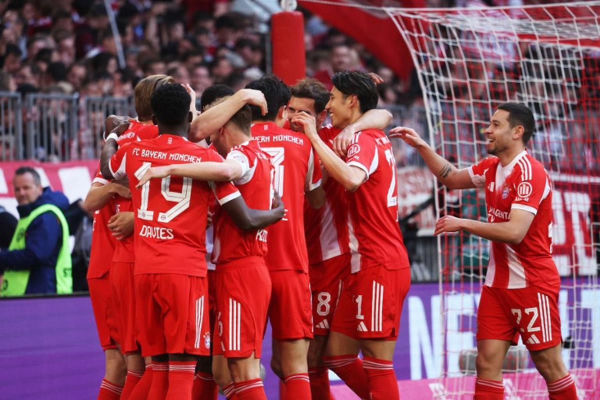 Bayern Munich's English forward #09 Harry Kane (L) celebrates with team mates after scoring the 4-1 goal as fans cheer in the background during the German first division Bundesliga football match between FC Bayern Munich and VfB Stuttgart in Munich, southern Germany, on April 19, 2026.  Karl-Josef HILDENBRAND / AFP